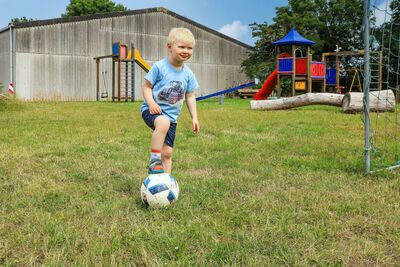 Junge mit Fußball auf dem Spielplatz